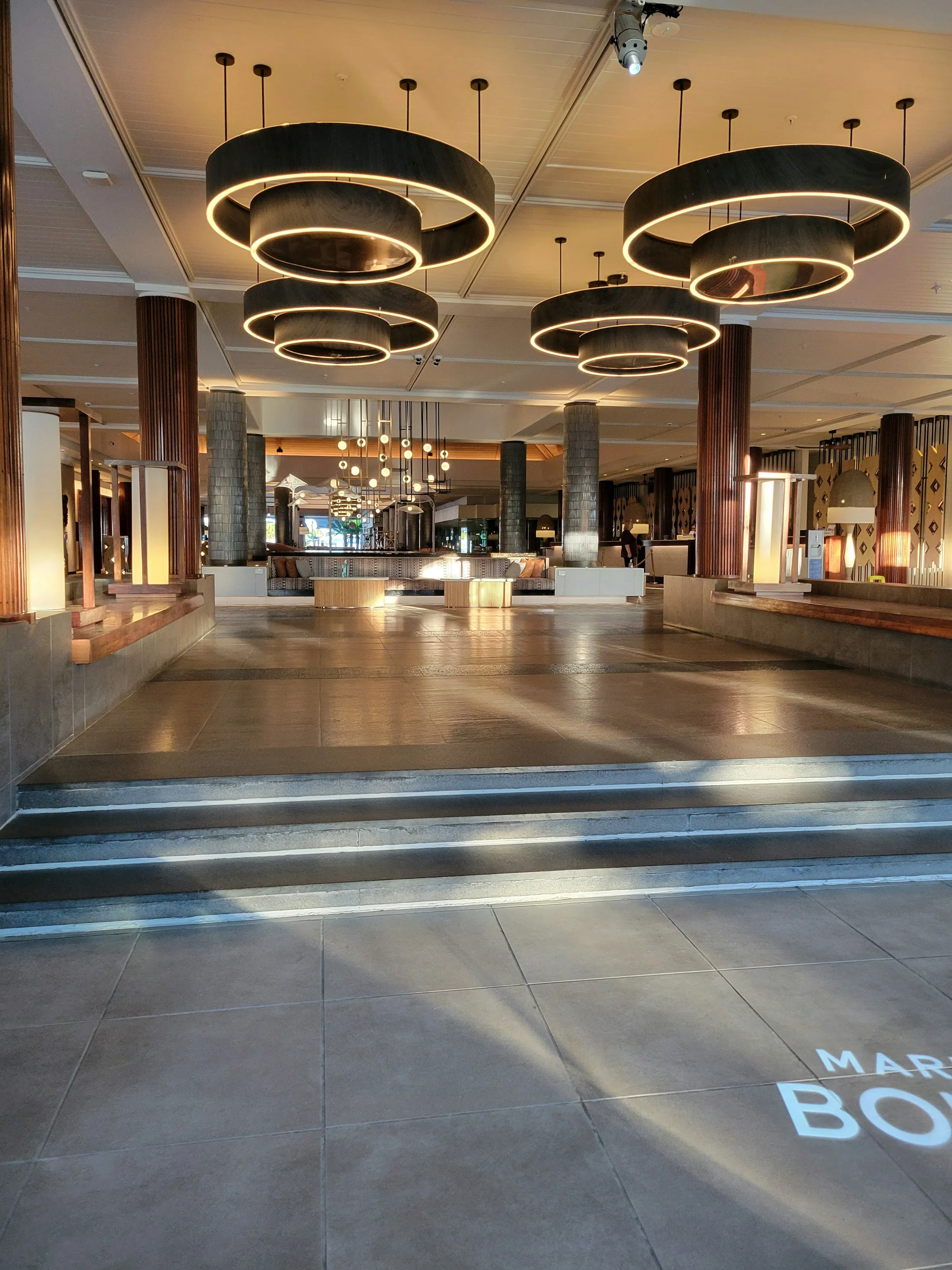 Large-format commercial flooring in a hospitality interior with architectural light from a tall window.