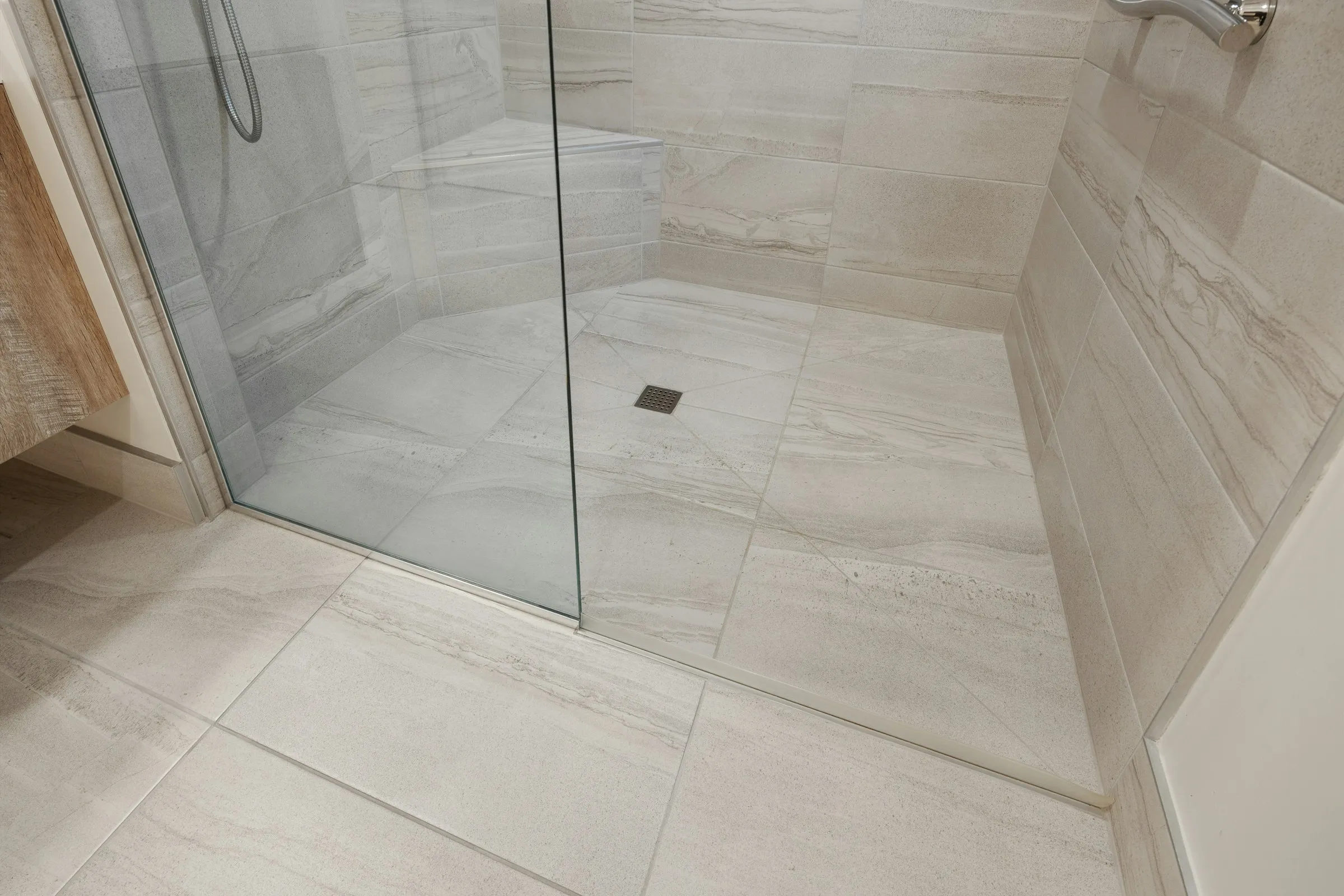 Large-format porcelain tile surface with cool grey-blue undertone in a modern wet-area-adjacent setting.